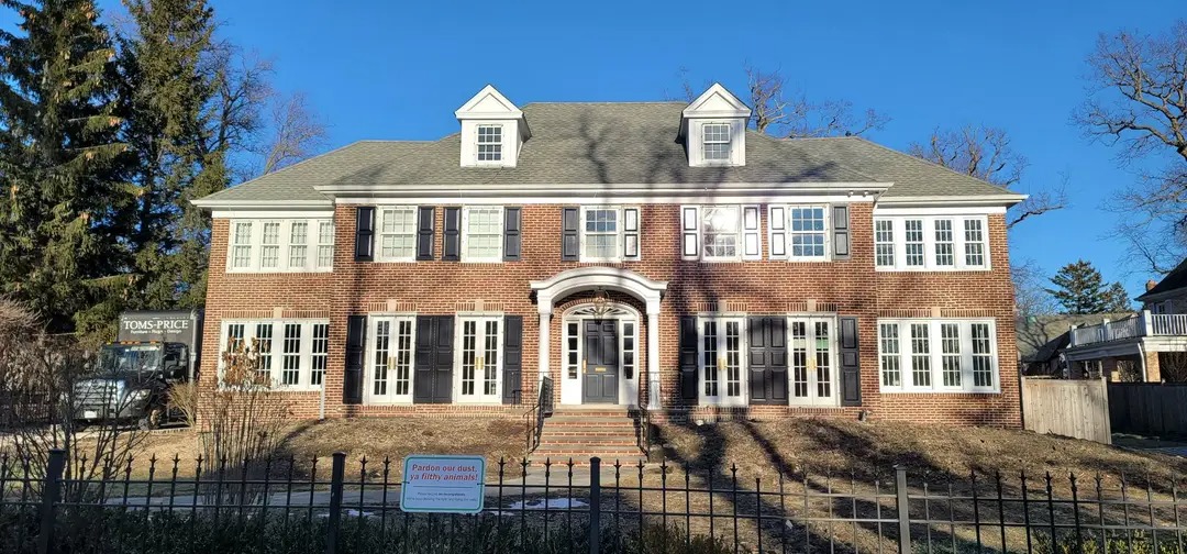 Red brick Georgian house with black shutters and a dark iron fence in Winnetka, Illinois